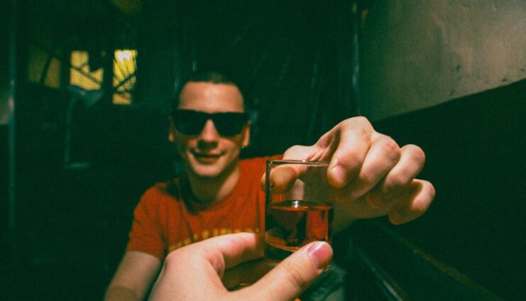 man in brown crew neck t-shirt holding clear drinking glass