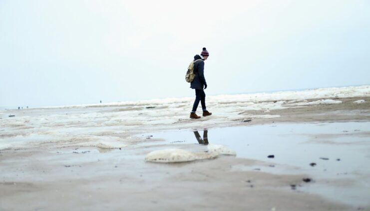 person in black jacket walking on beach during daytime